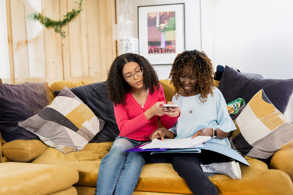 Mother and daughter sitting of a couch taking a photo of a document