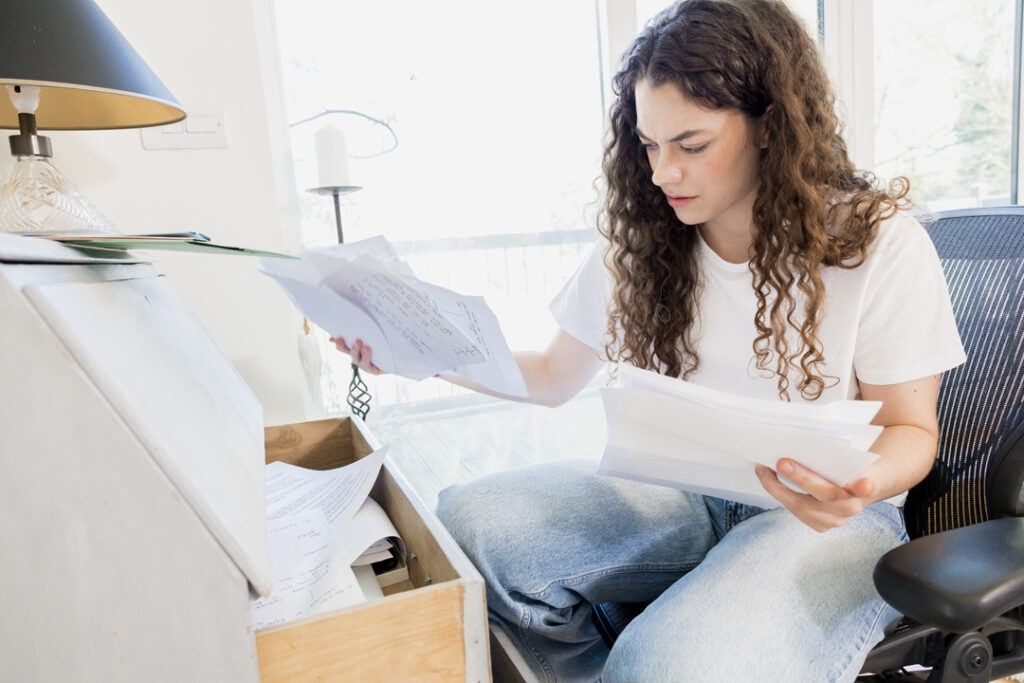 A young adult reviewing papers from a filing cabinet